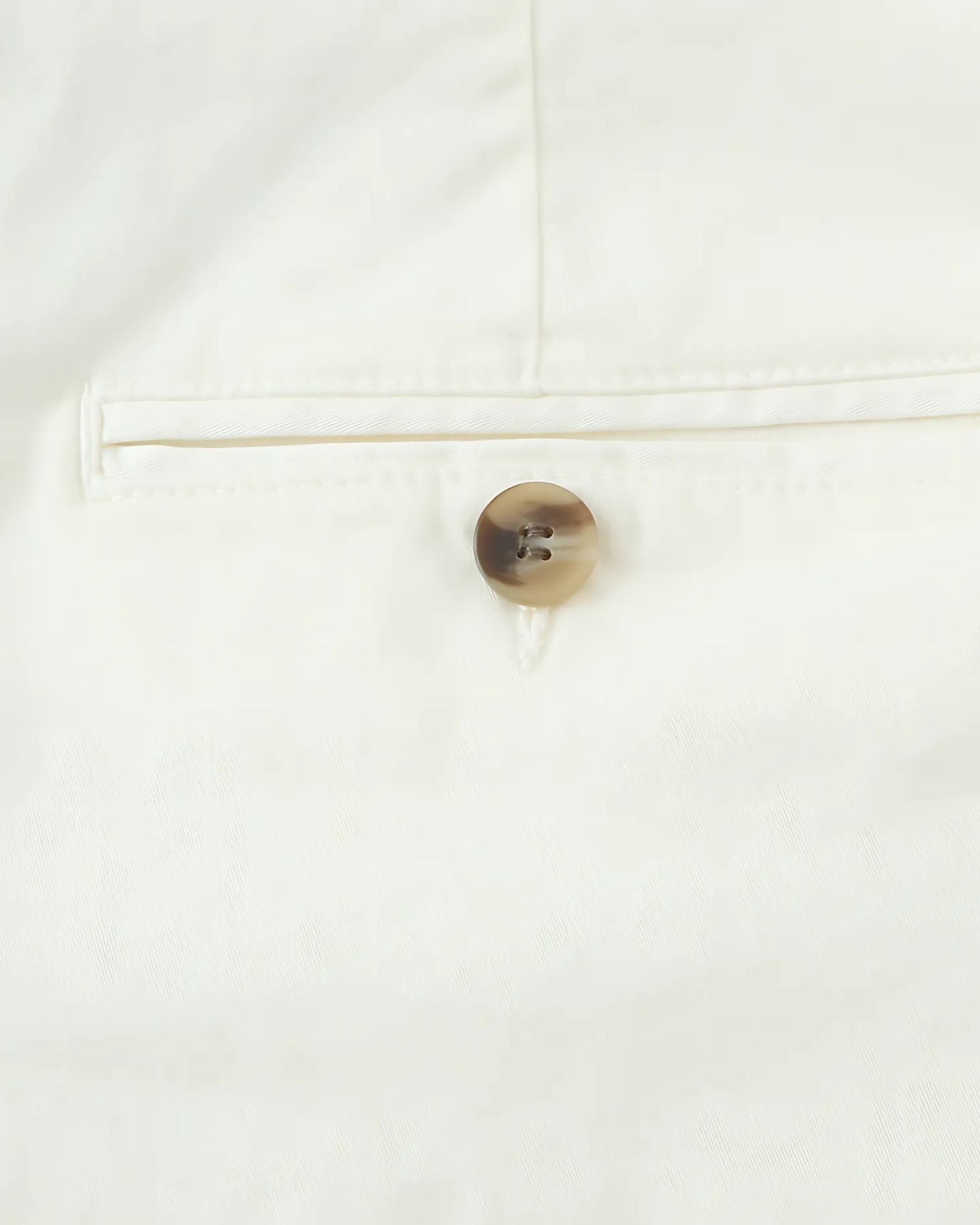 Round button in a matching color discreetly sewn on the waistband for subtle elegance