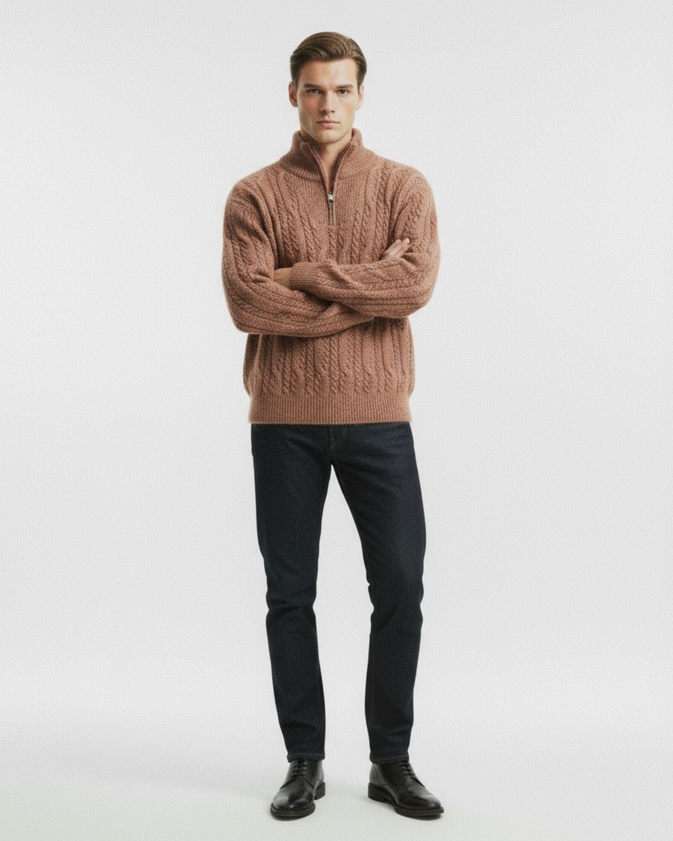 Man wearing a brown cable knit sweater and black pants on a white background