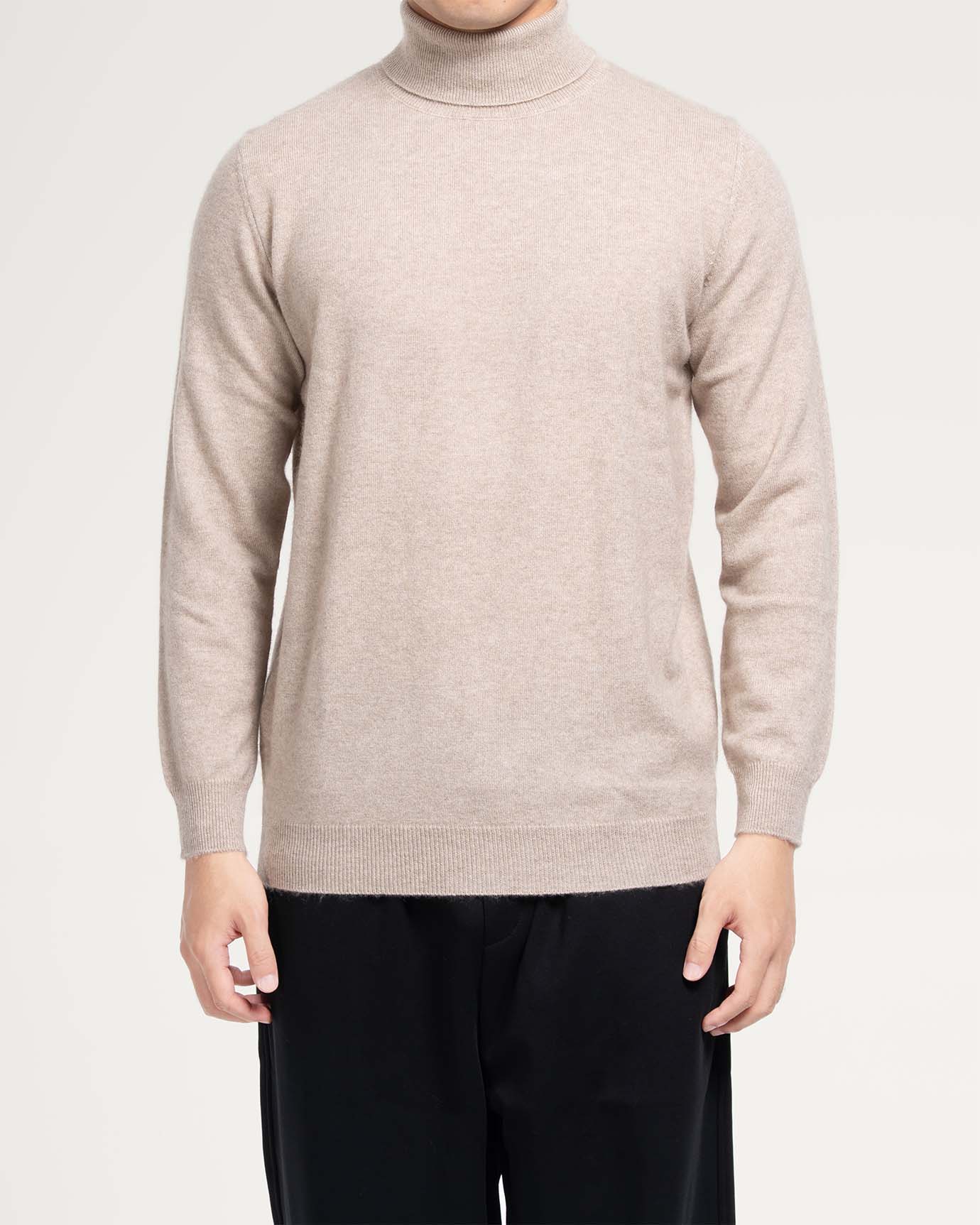 Model wearing camel turtleneck sweater in soft cashmere fabric
