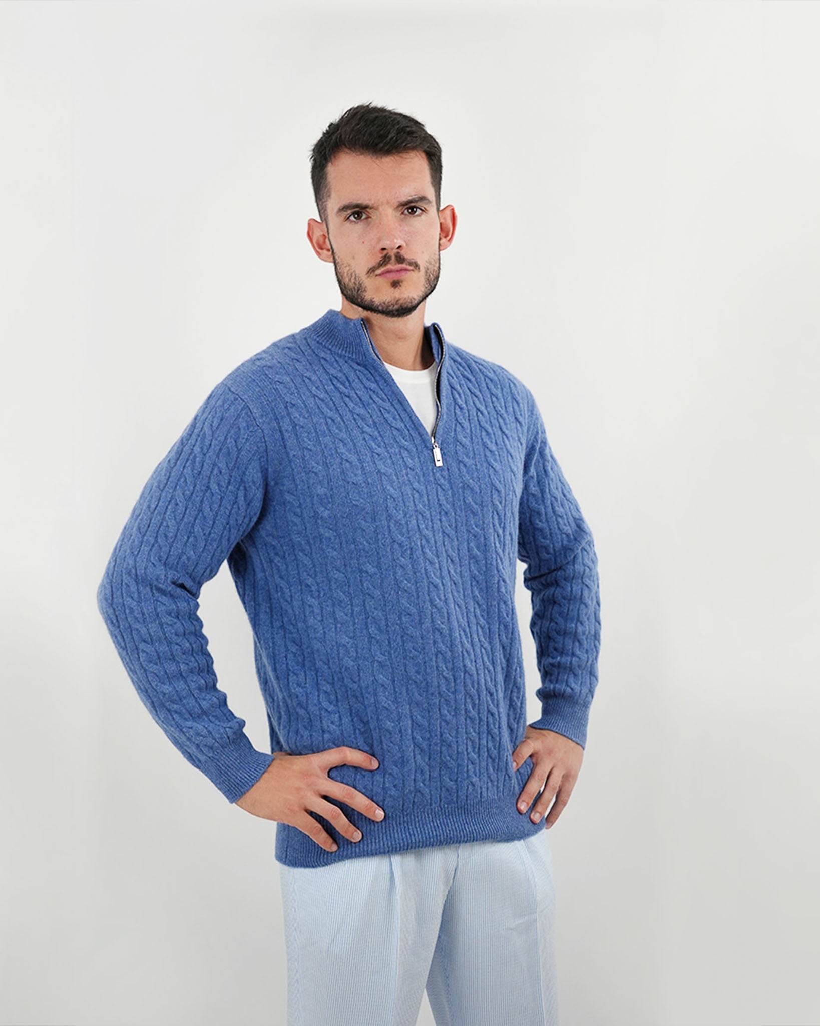 Man wearing a blue cable knit sweater against a white background