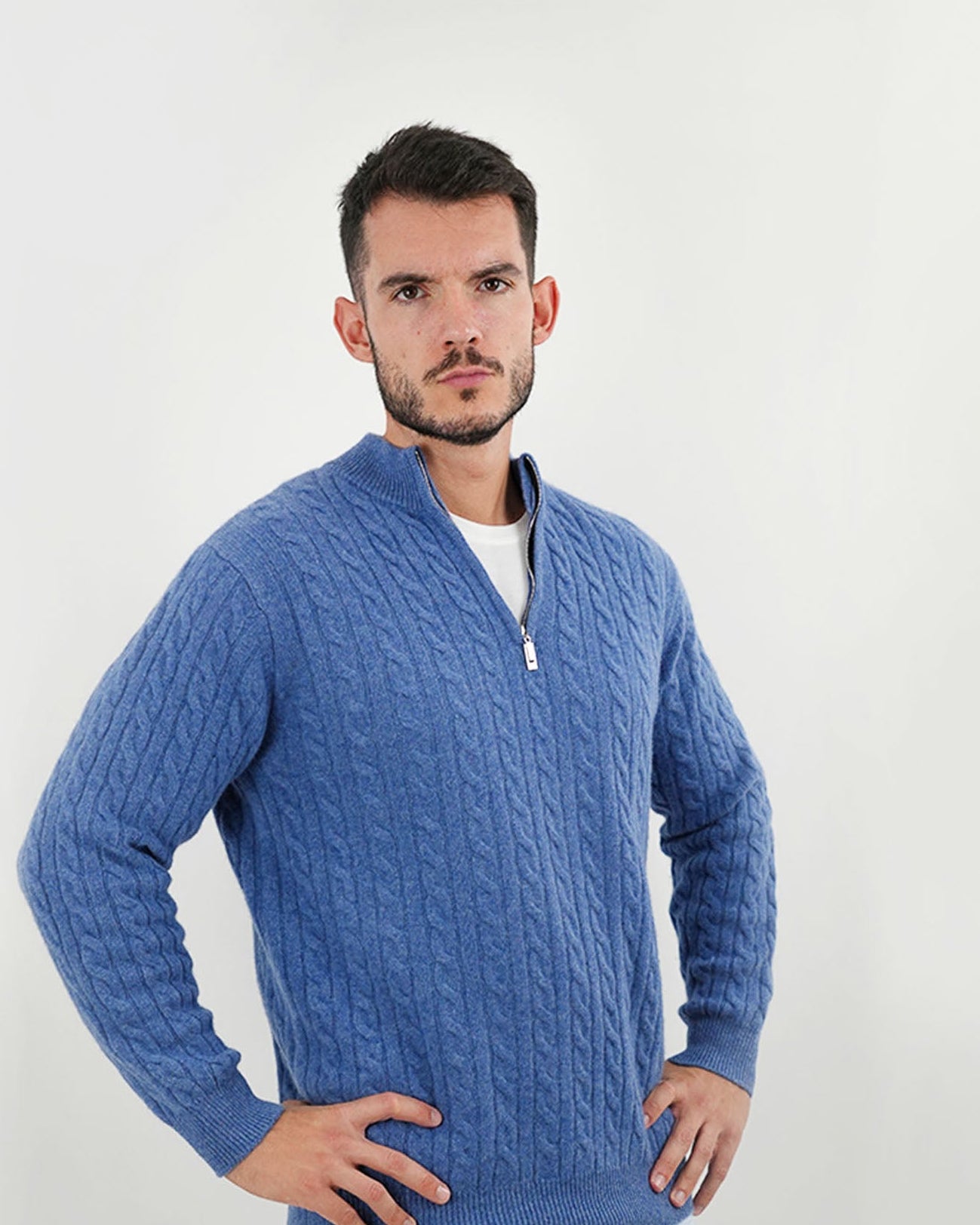 Man wearing a blue cable knit sweater against a white background