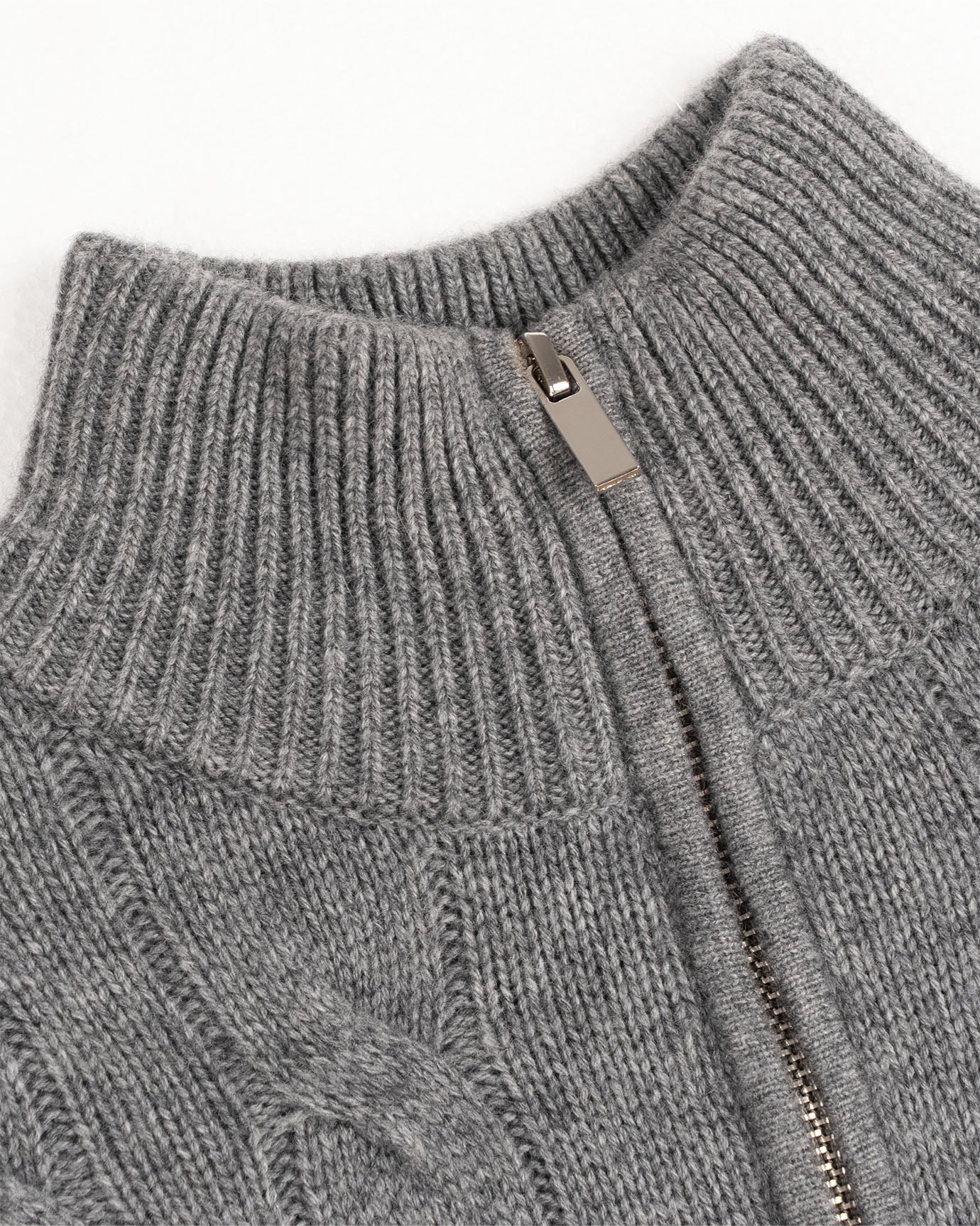 Close-up of a gray knit sweater with a zipper detail on a white background