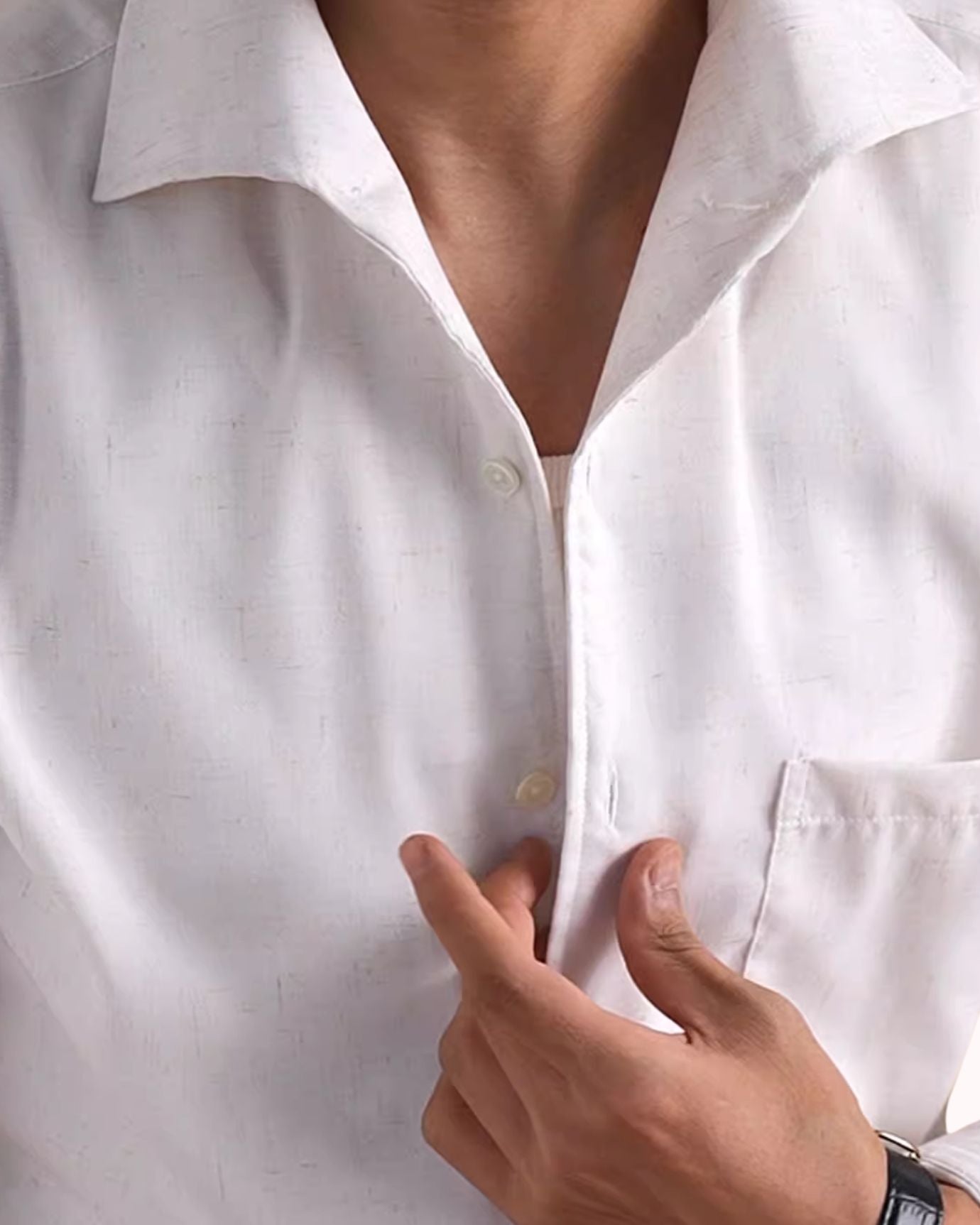 Close-up of a white shirt with a hand pointing to a button
