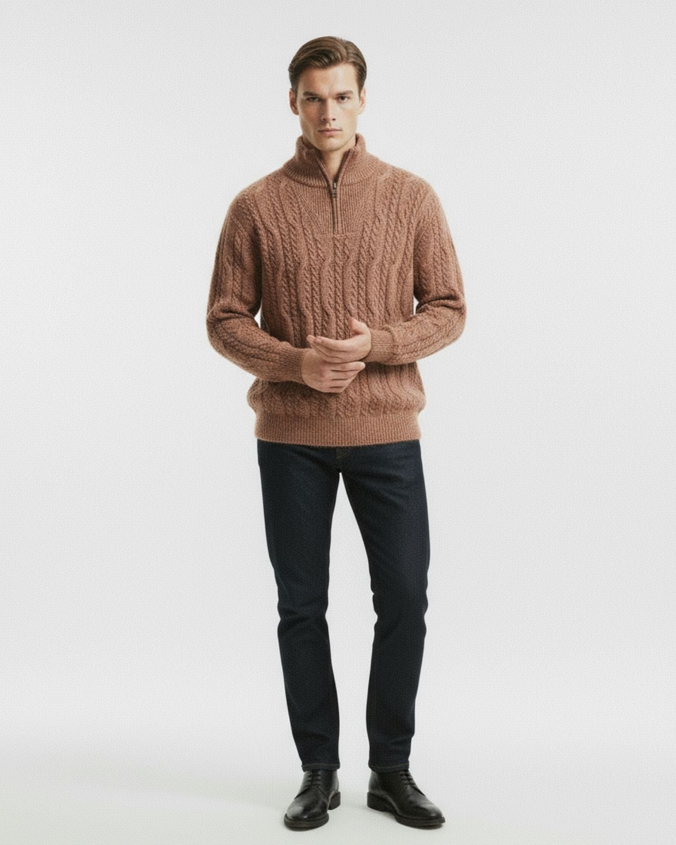Man wearing a brown cable knit sweater and black pants on a white background