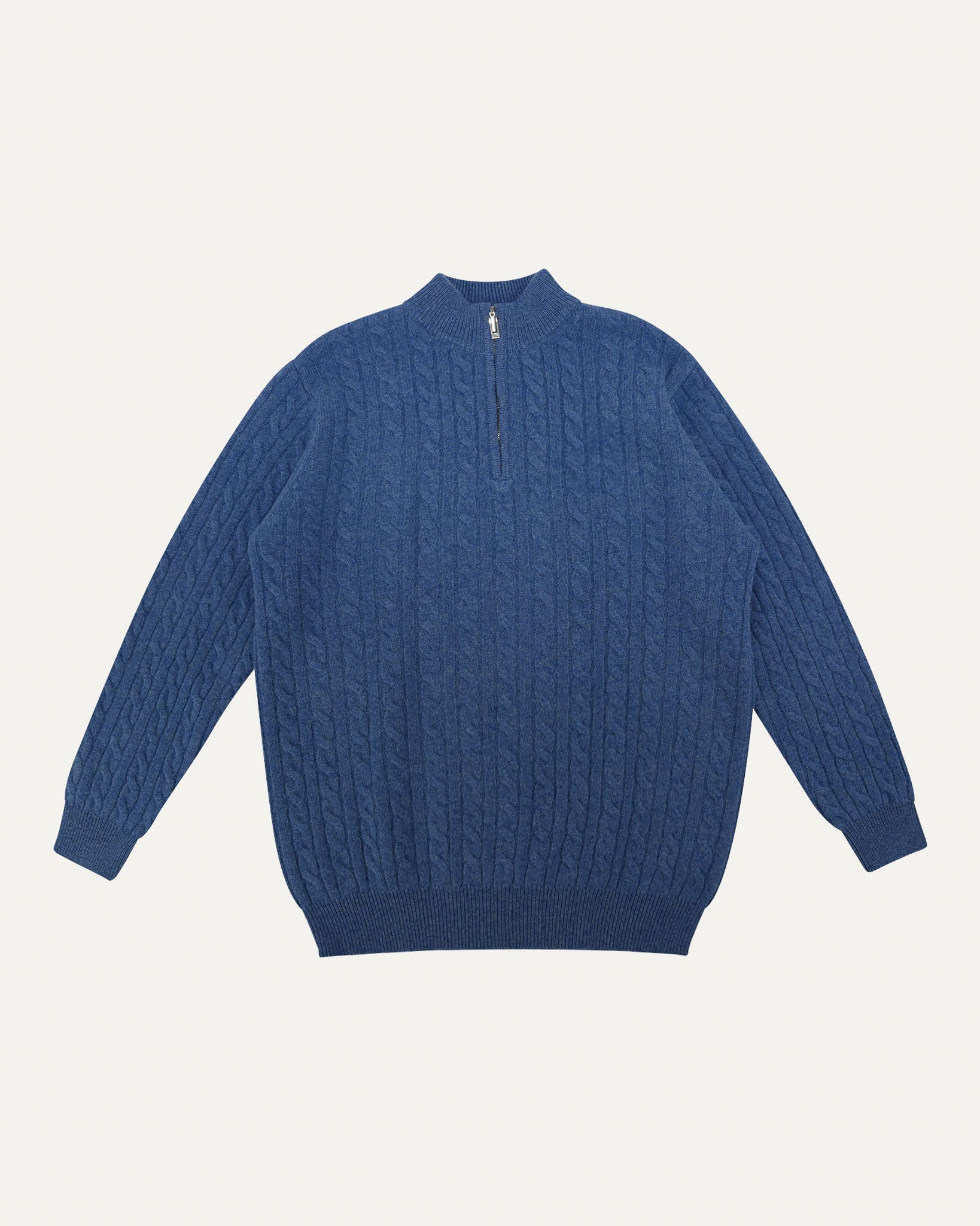 Blue cable knit sweater on a light gray background

